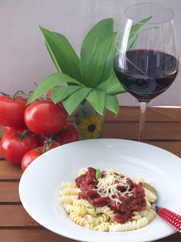 Gemüsebolognese mit Nudeln und einem Glas Rotwein